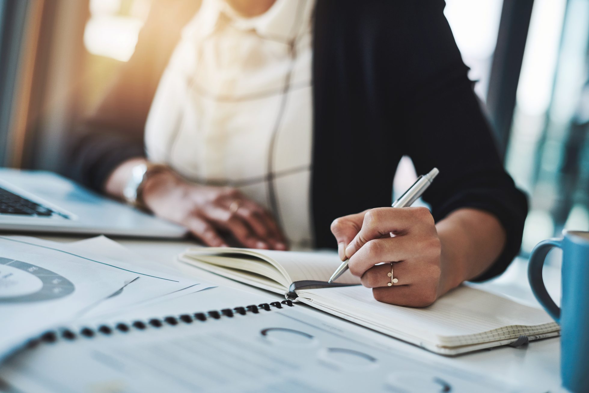 Cropped shot of a businesswoman making notes at her desk in a modern office