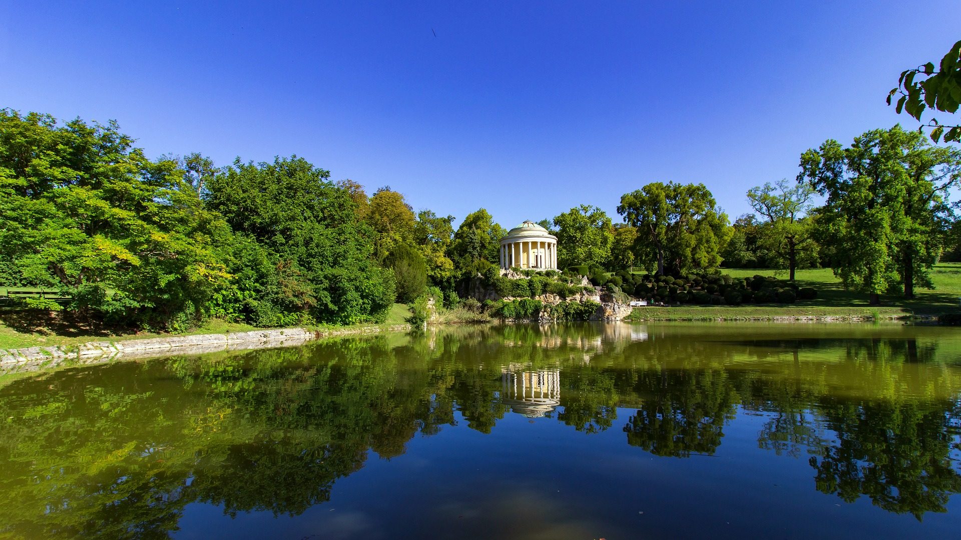 Park w Eisenstadt. Zielona trawa, drzewa, ławki i alejki. Spokojna atmosfera.
