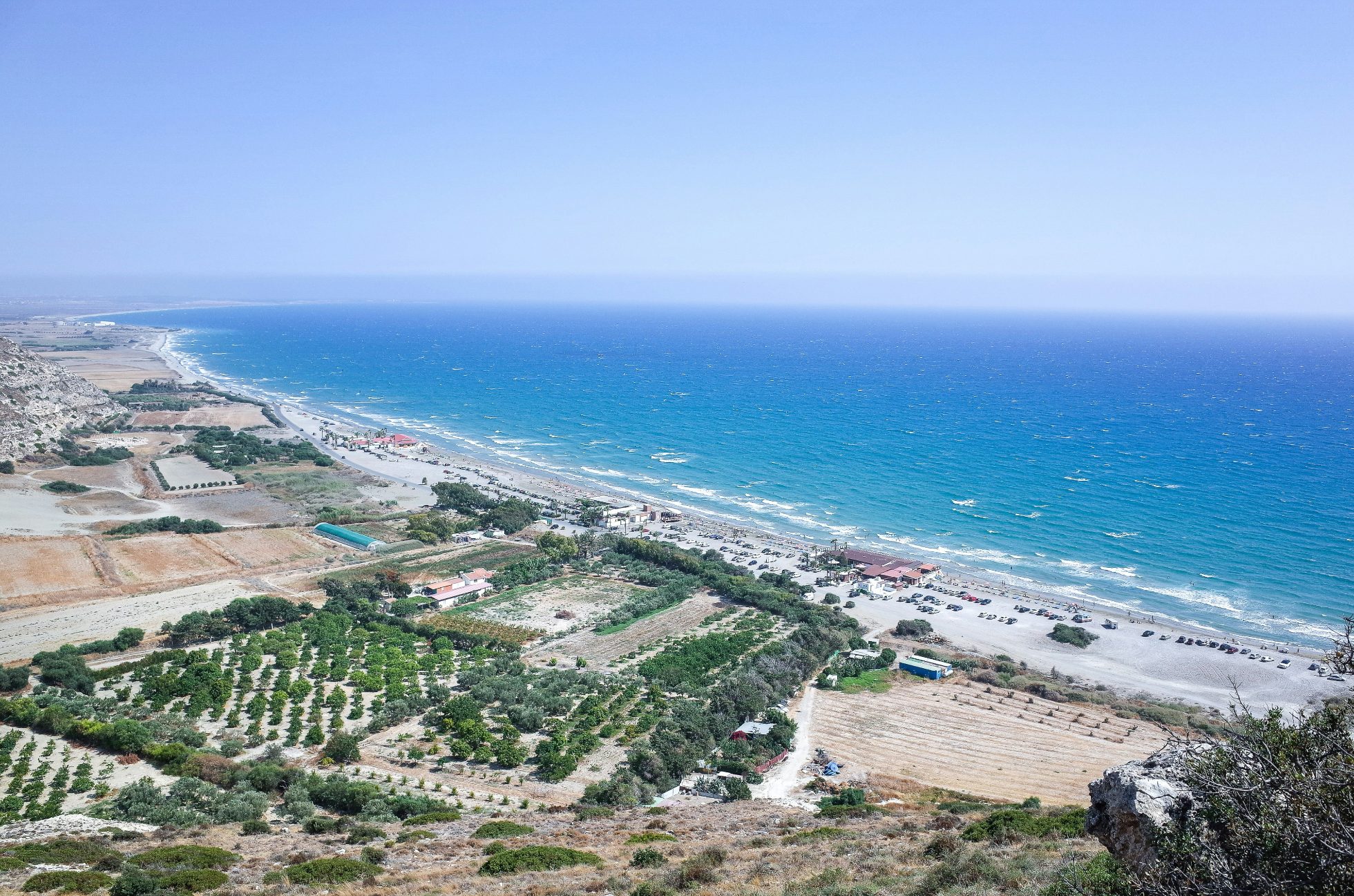 Plaża Kourion na Cyprze - błękitne morze, złoty piasek i skały w tle.