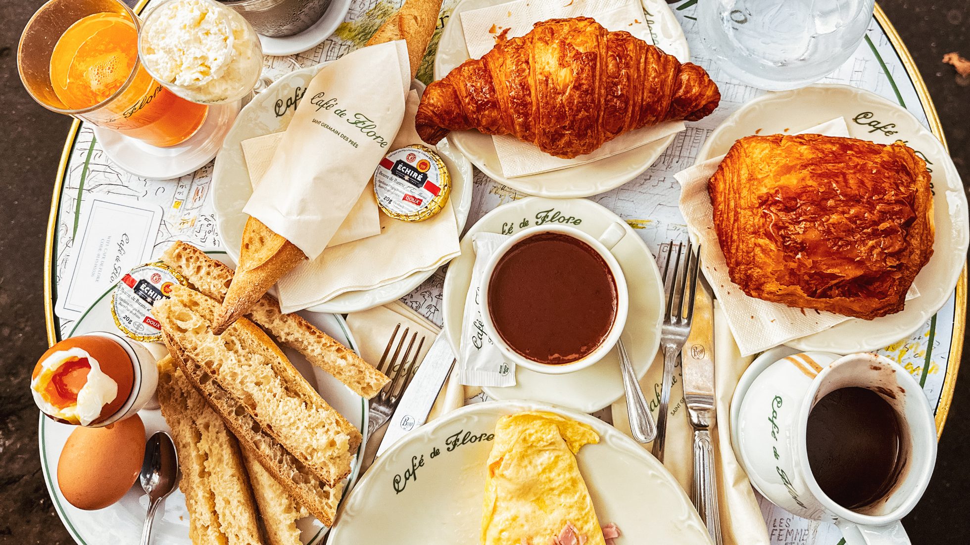 francuskie śniadanie - croissant, omlet, bagietka, sok, jajka na miękko oraz czekolada na stola