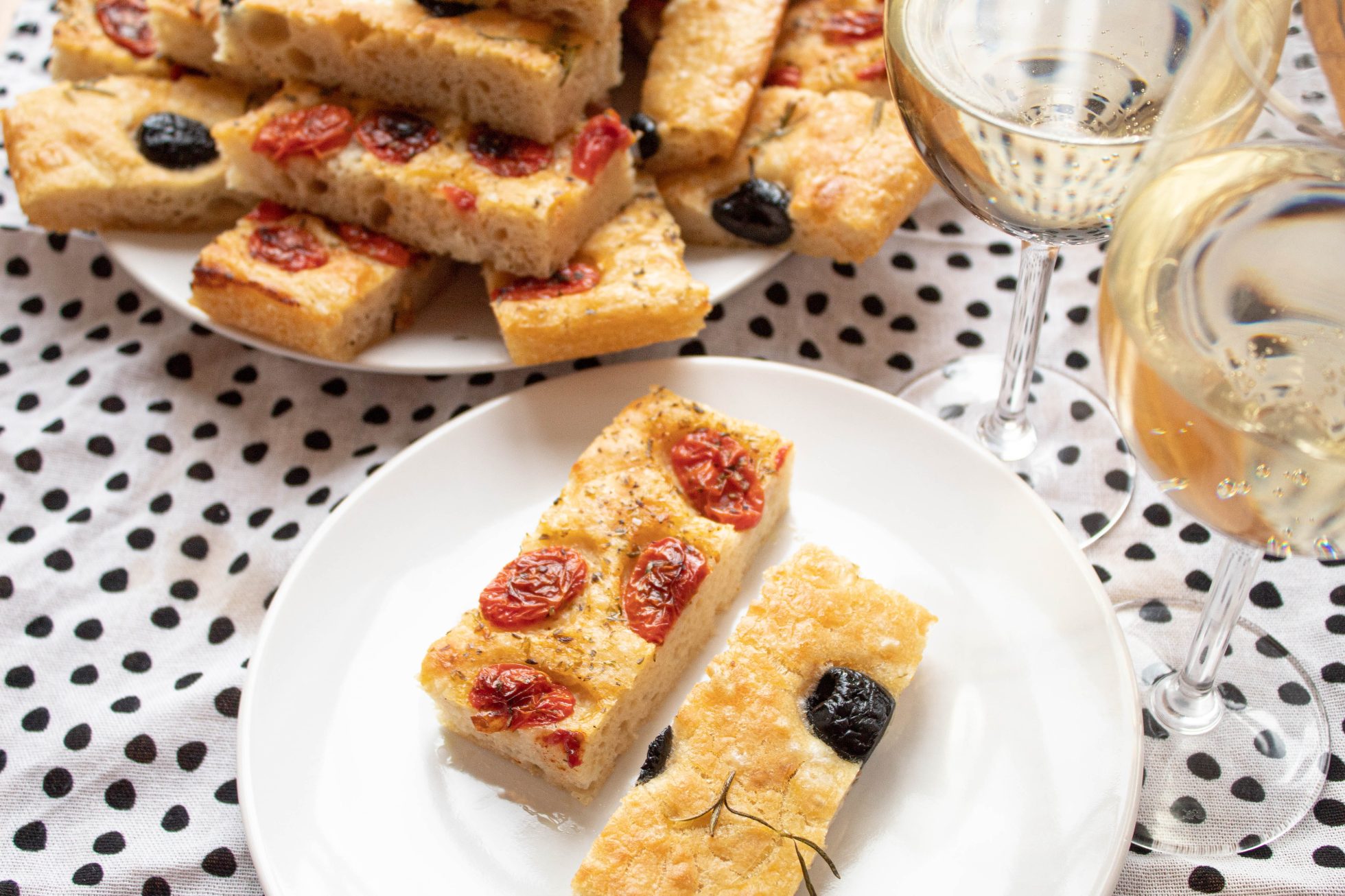 Włoska focaccia z suszonymi pomidorami i czarnymi oliwkami podana na białym porcelanowym talerzu