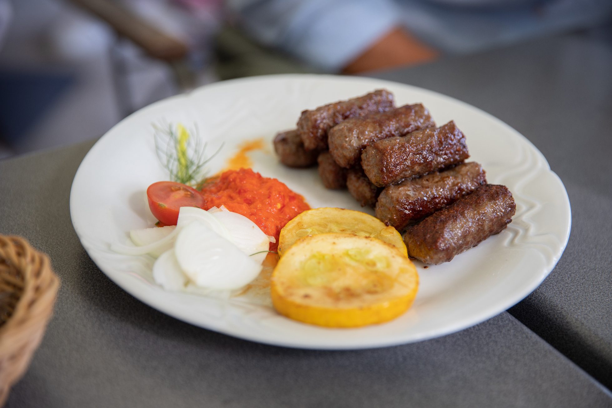 Grillowane paluszki ćevapi z ajwarem i warzywami na talerzu - typowe dania Zagrzebia