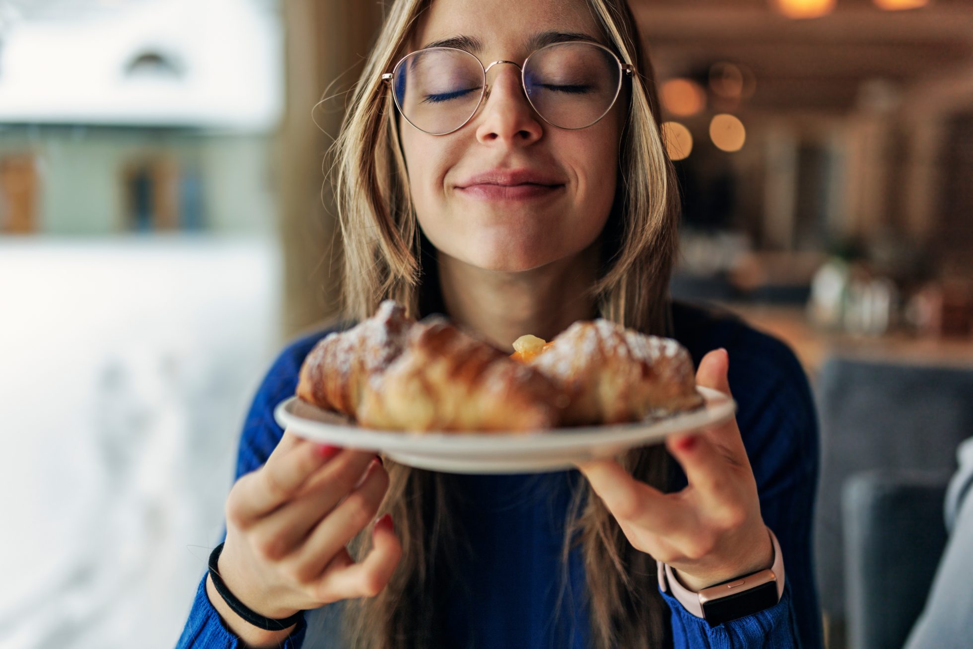 Młoda dziewczyna trzyma pachnące rogaliki w restauracji