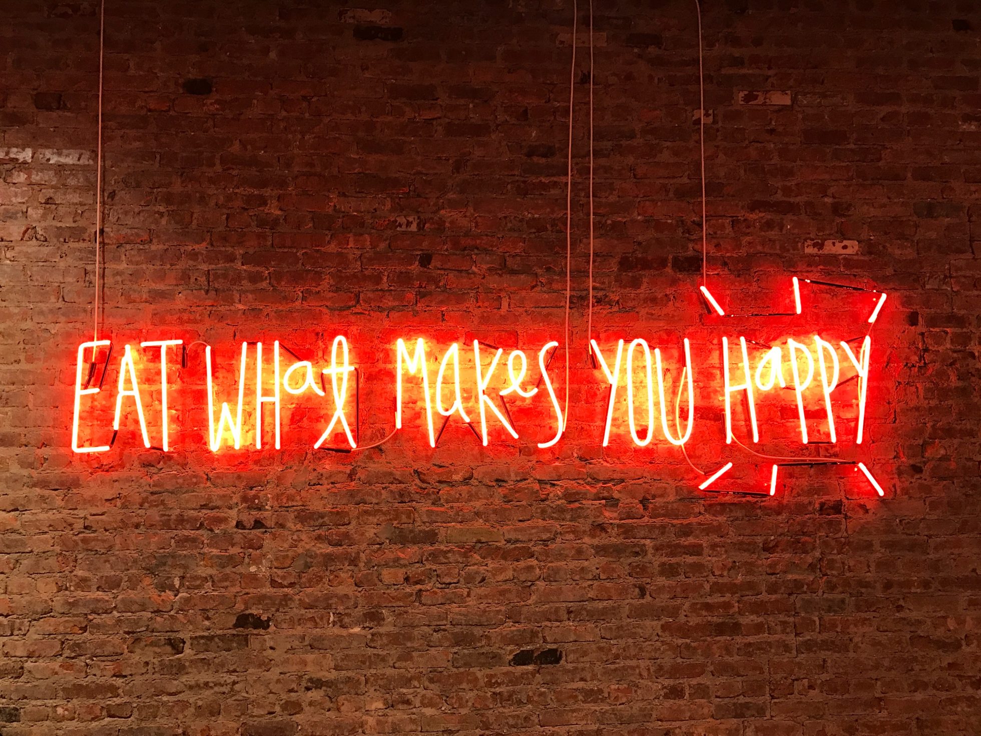 Neon w restauracji z angielskim zdaniem: Eat what makes you happy