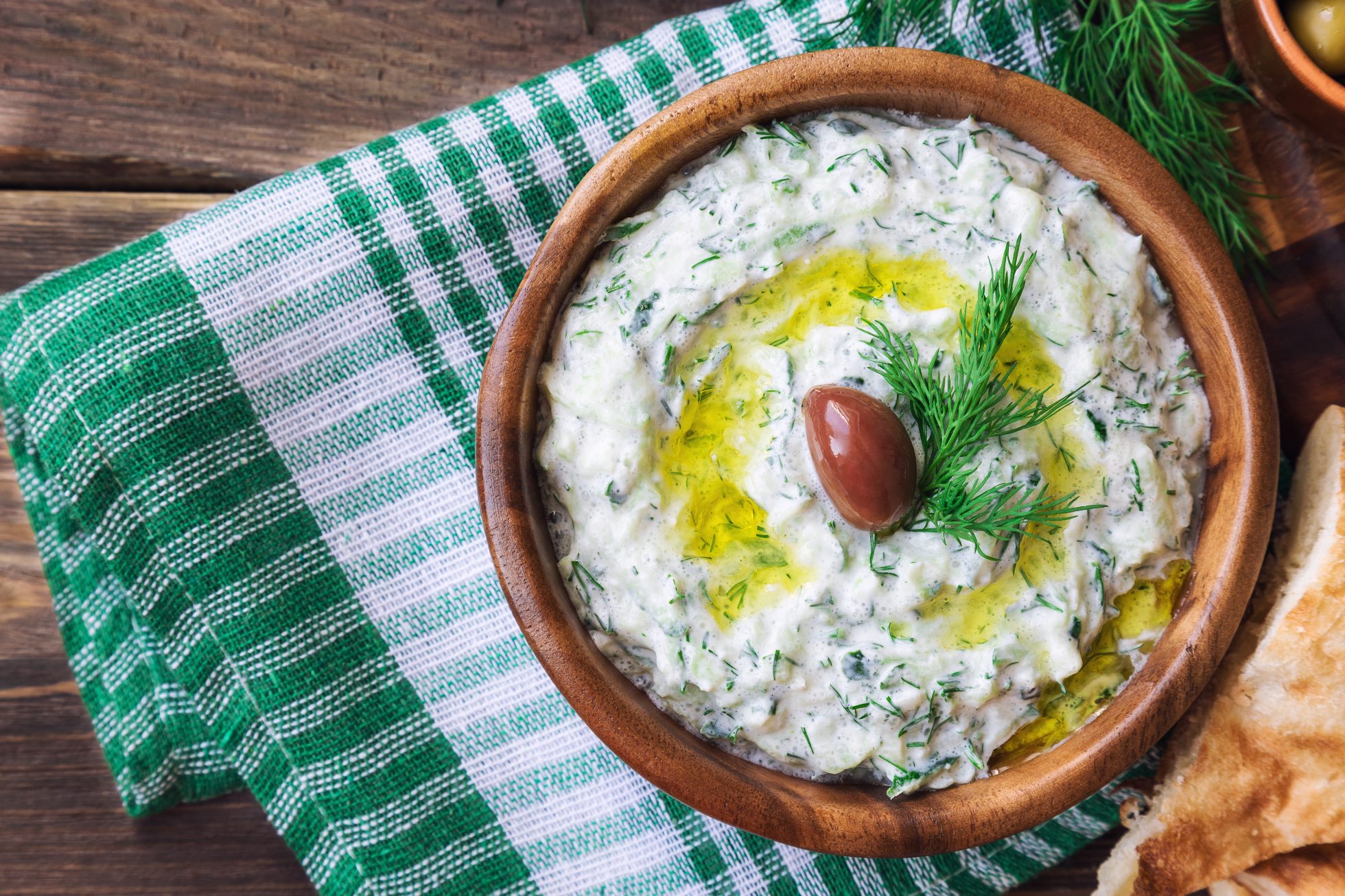Miska z sosem tzatziki na tle greckiej flagi.