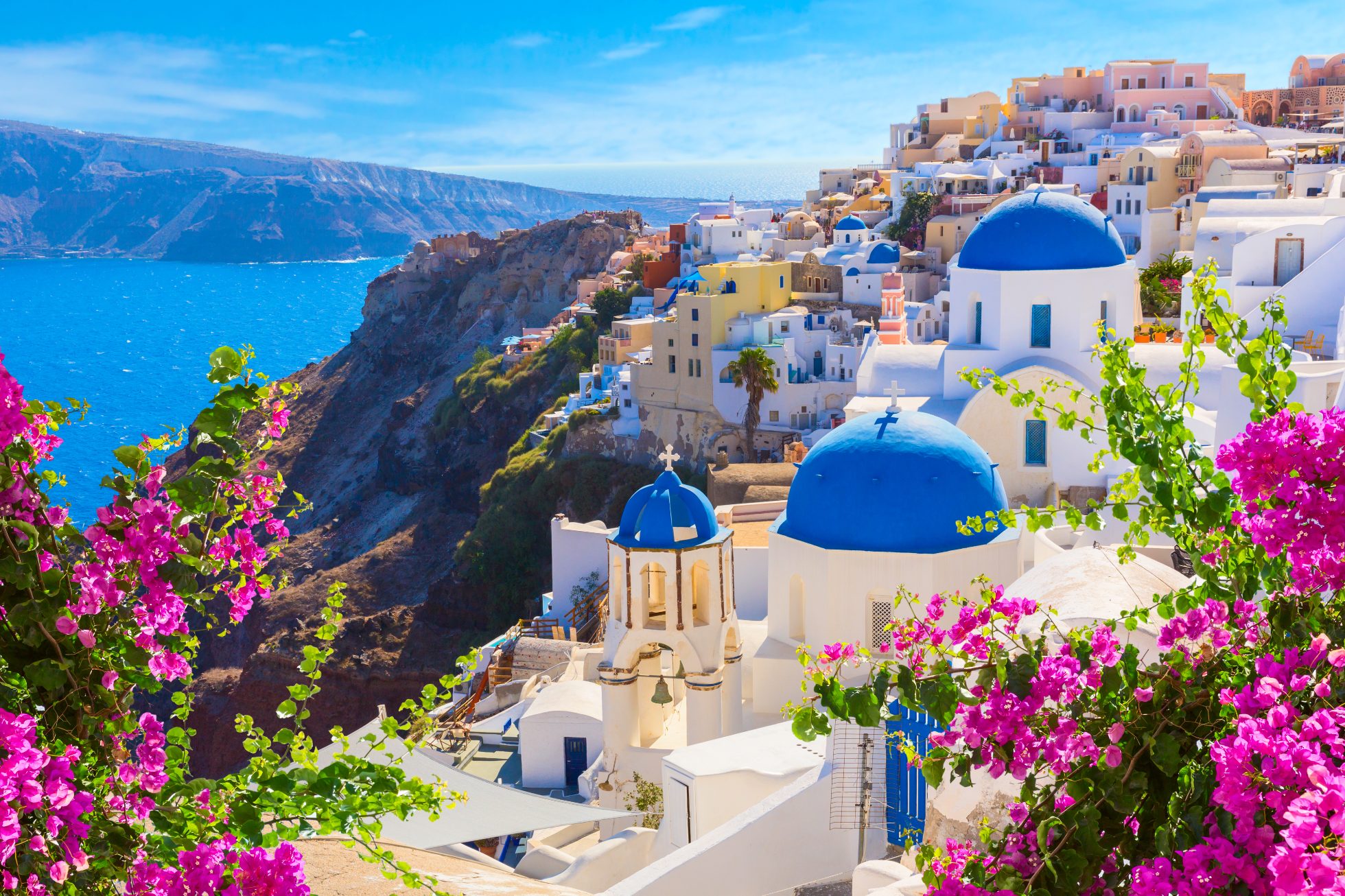 Wyspa Santorini, Grecja. Tradycyjne białe domy i kościoły z niebieskimi kopułami w mieście Oia nad Kalderą, Morze Egejskie.