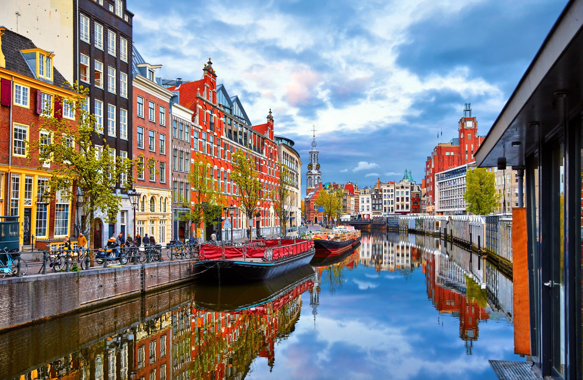 Łodzie na tle domów nad rzeką Amstel w Amsterdamie, Holandia