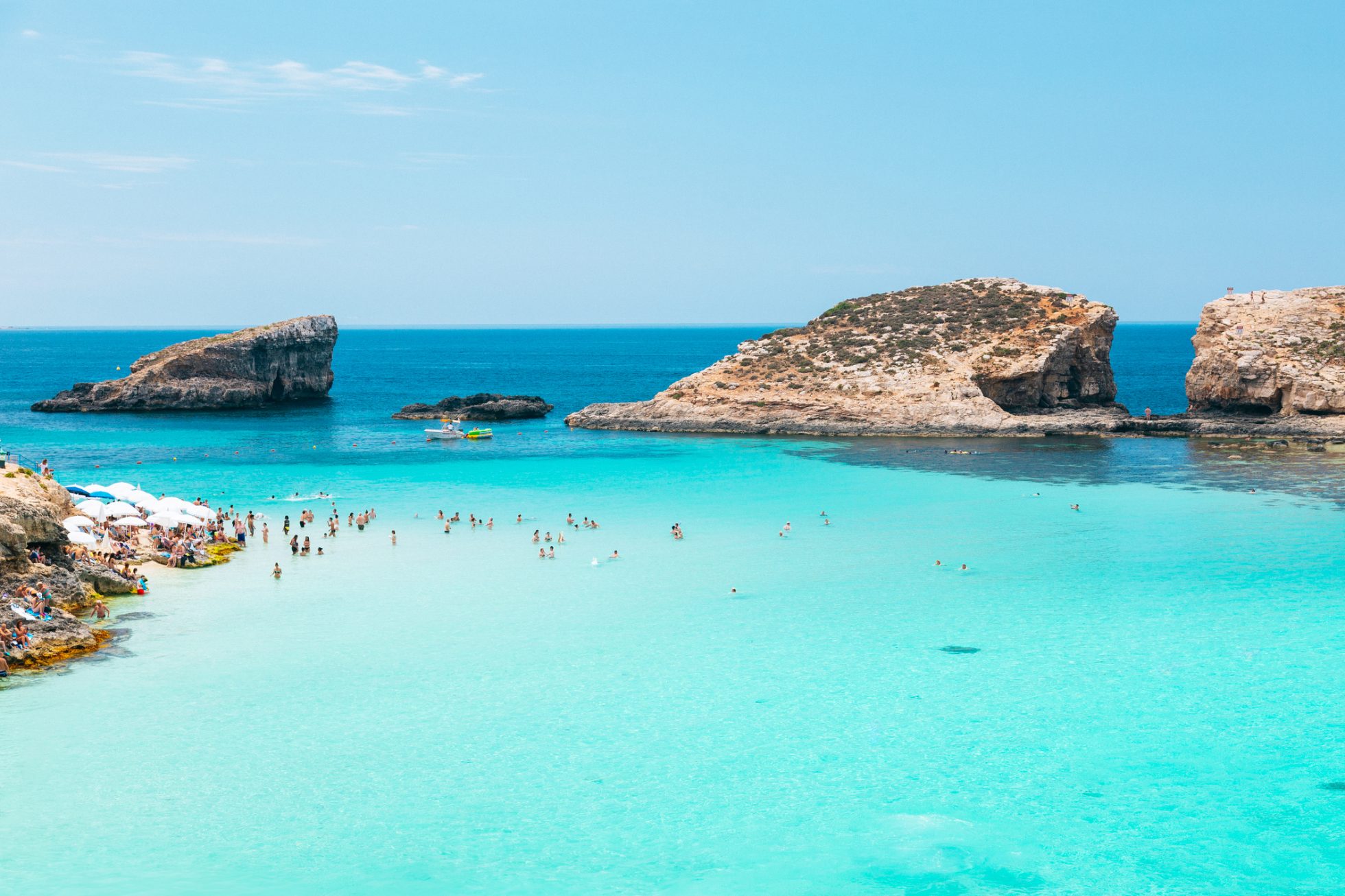 Piękna plaża Blue Lagoon na wyspie Comino z krystalicznie czystą wodą i formacjami skalnymi w tle.
