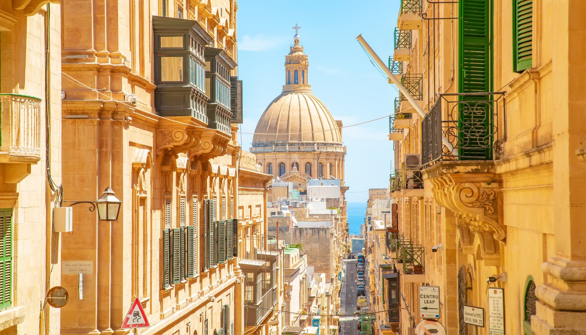 Słoneczna ulica w starym mieście Valletta na Malcie. W tle Bazylika Matki Bożej z Góry Karmel.