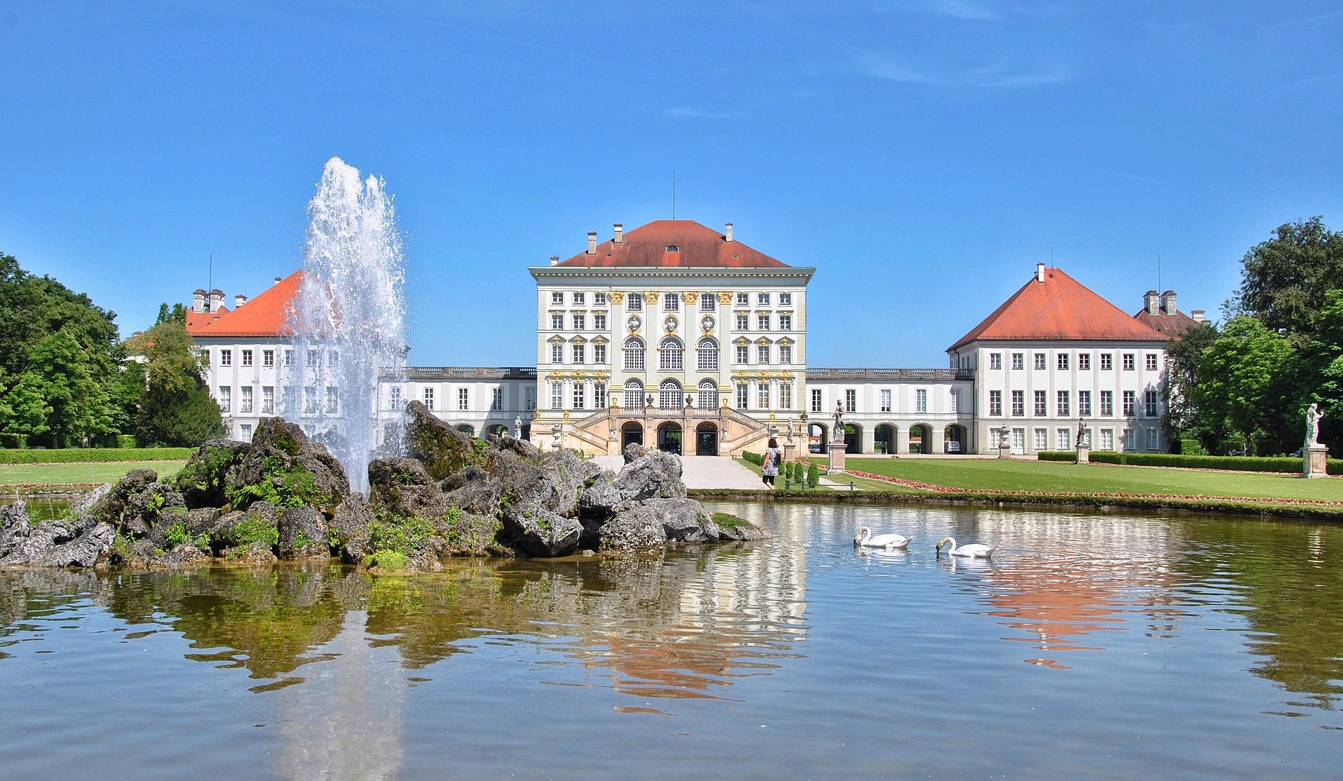 Biały pałac i fontanna na pierwszym planie w słoneczny dzień