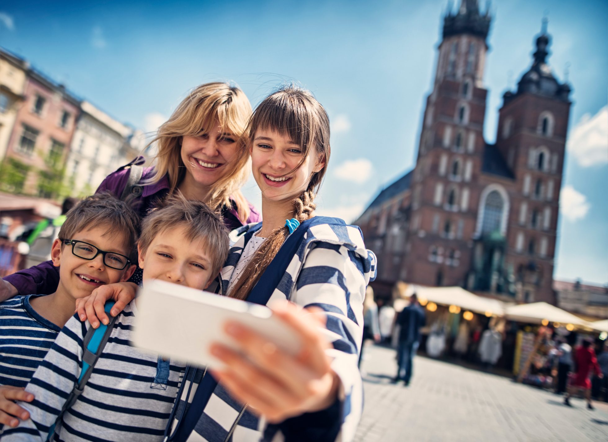 A mother and her children taking a selfie in front of St. Mary's Basilica in the Main Market Square in Krakow.