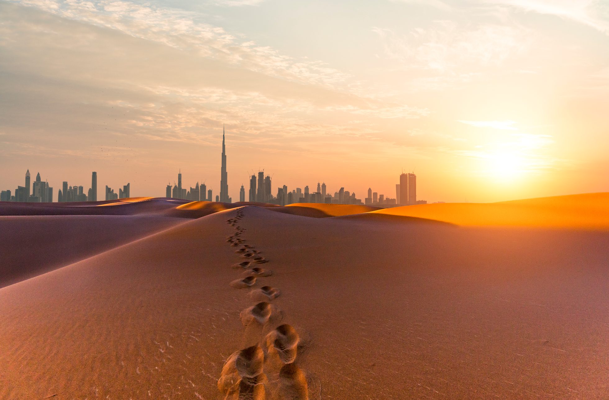 panorama Dubaju z pustynią i nowoczesnym centrum biznesowym w tle o wschodzie słońca - loty na Bliski Wschód