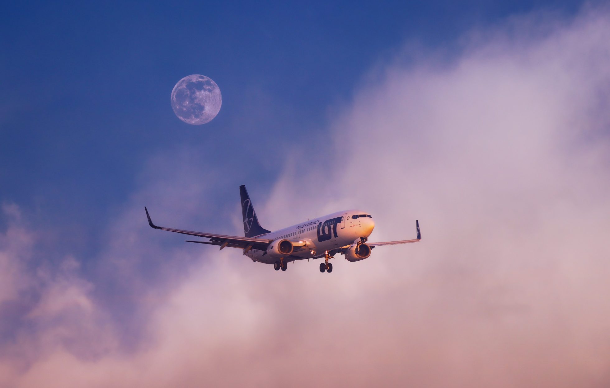 Boeing 737 lądujący na Lotnisku Chopina z księżycem i chmurami w tle