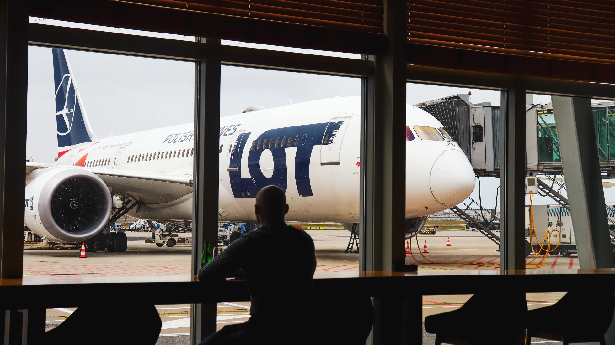 Okna panoramiczne z widokiem na 787 Dreamlinera stojącego na płycie lotniska - LOT Business Lounge Mazurek