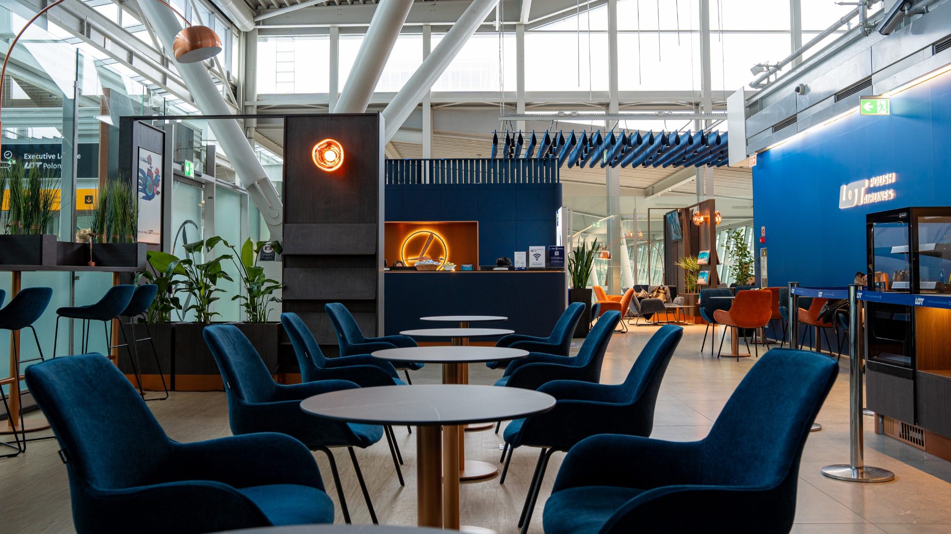 LOT Business Lounge Polonez - Recepcja, otwarta przestrzeń ze stolikami i fotelami w kolorze granatowym.