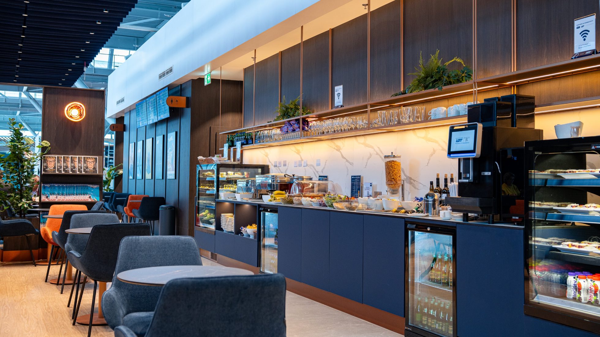 Luksusowa strefa wypoczynku w LOT Business Lounge Polonez - przy strefie restauracyjnej stoliki kawowe z granatowymi fotelami.