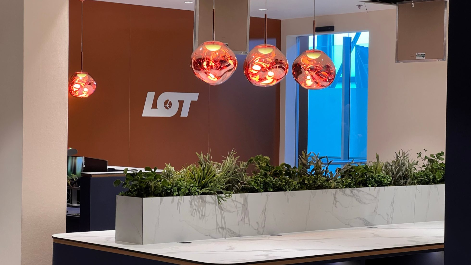 Elegancko urządzona przestrzeń z podłużnym blatem, roślinami i oświetleniem w Polonez Gold Lounge