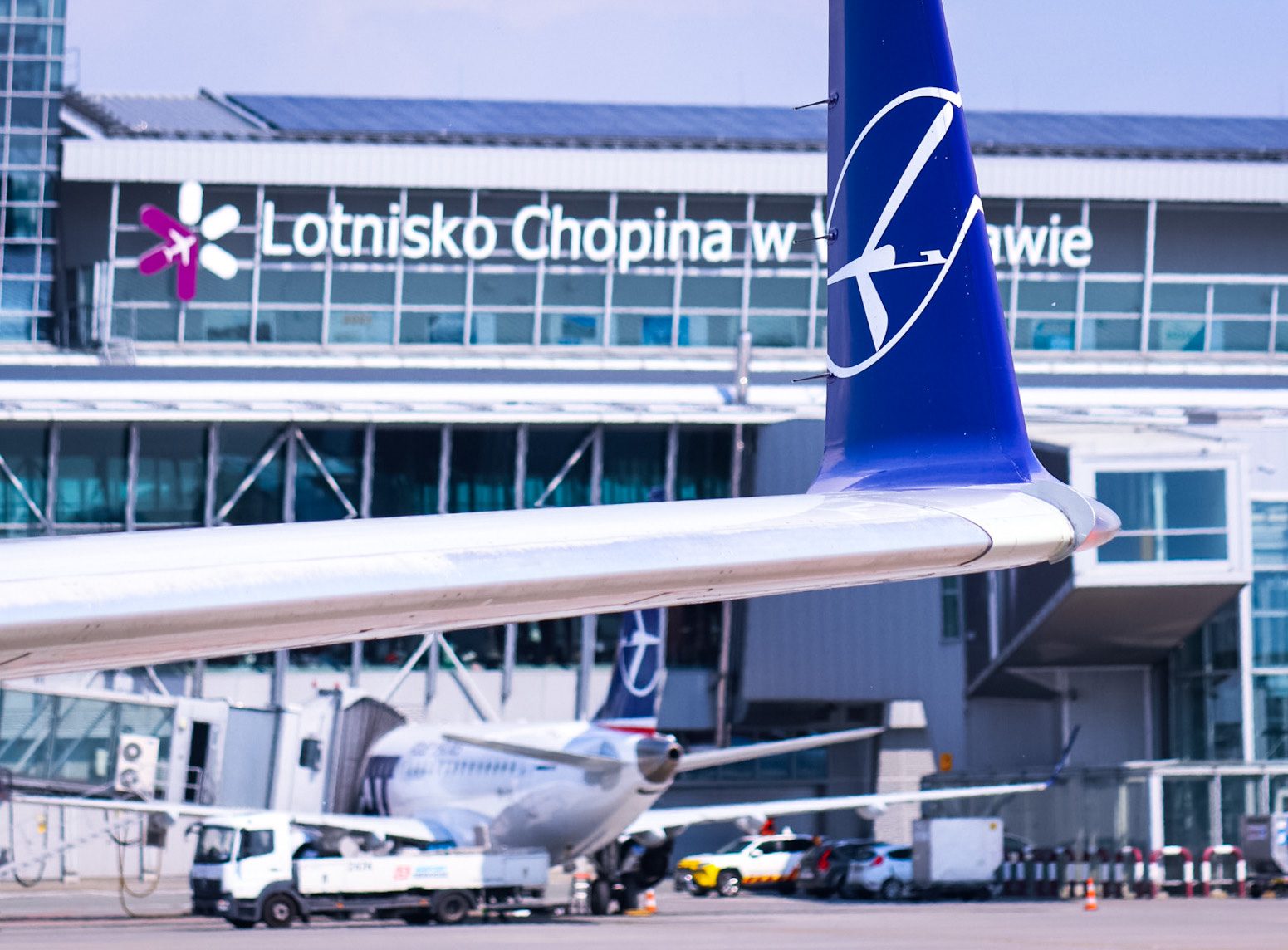 Terminal lotniska Chopina z widokiem na samoloty na pasie startowym.