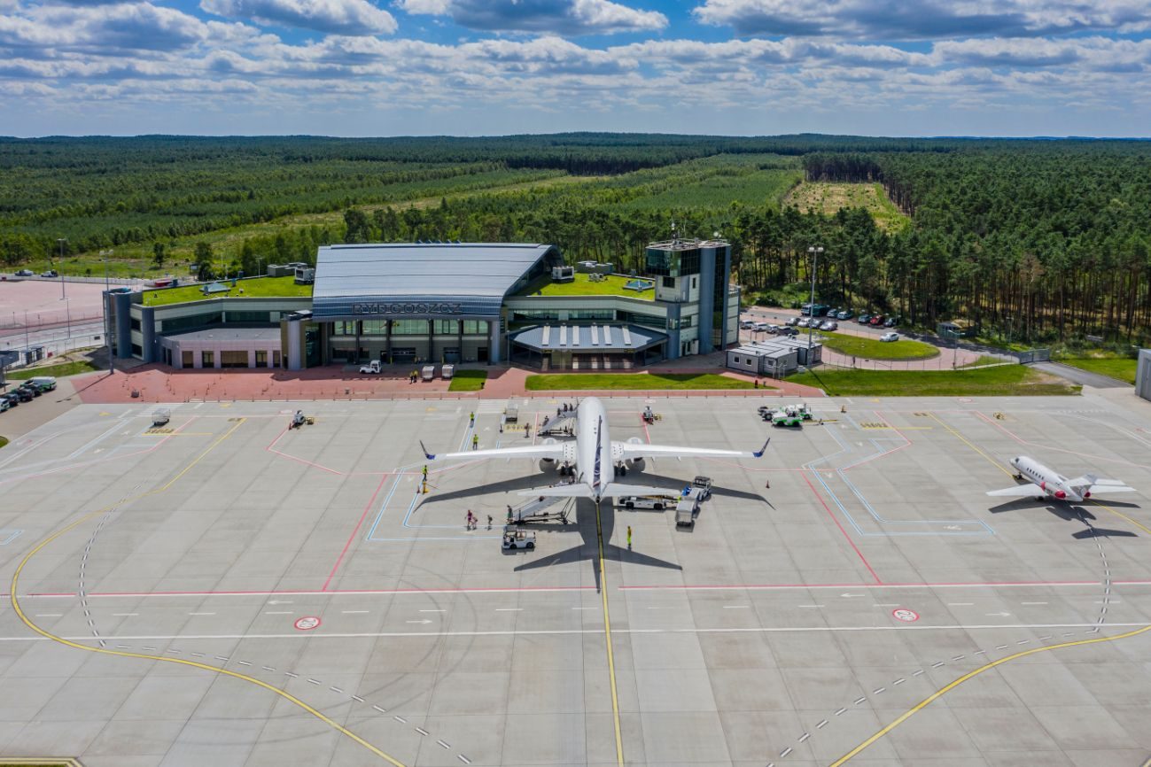 Widok na lotnisko w Bydgoszczy. W tle zielone pola i samolot