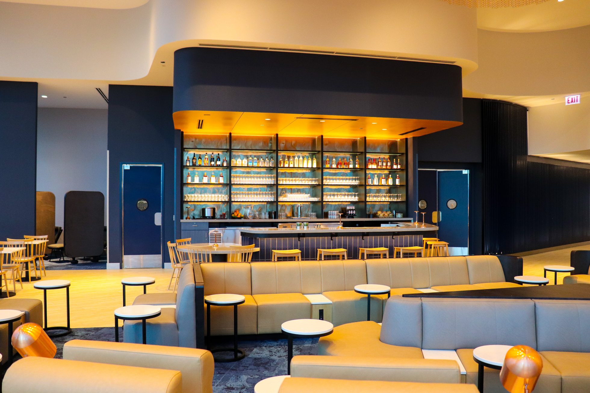 Elegancki Bar w Saloniku Biznesowym na lotnisku w Chicago na granatowej ścianie, wewnąrz ciepłe eleganckie oświetlenie i krzesła wokół baru