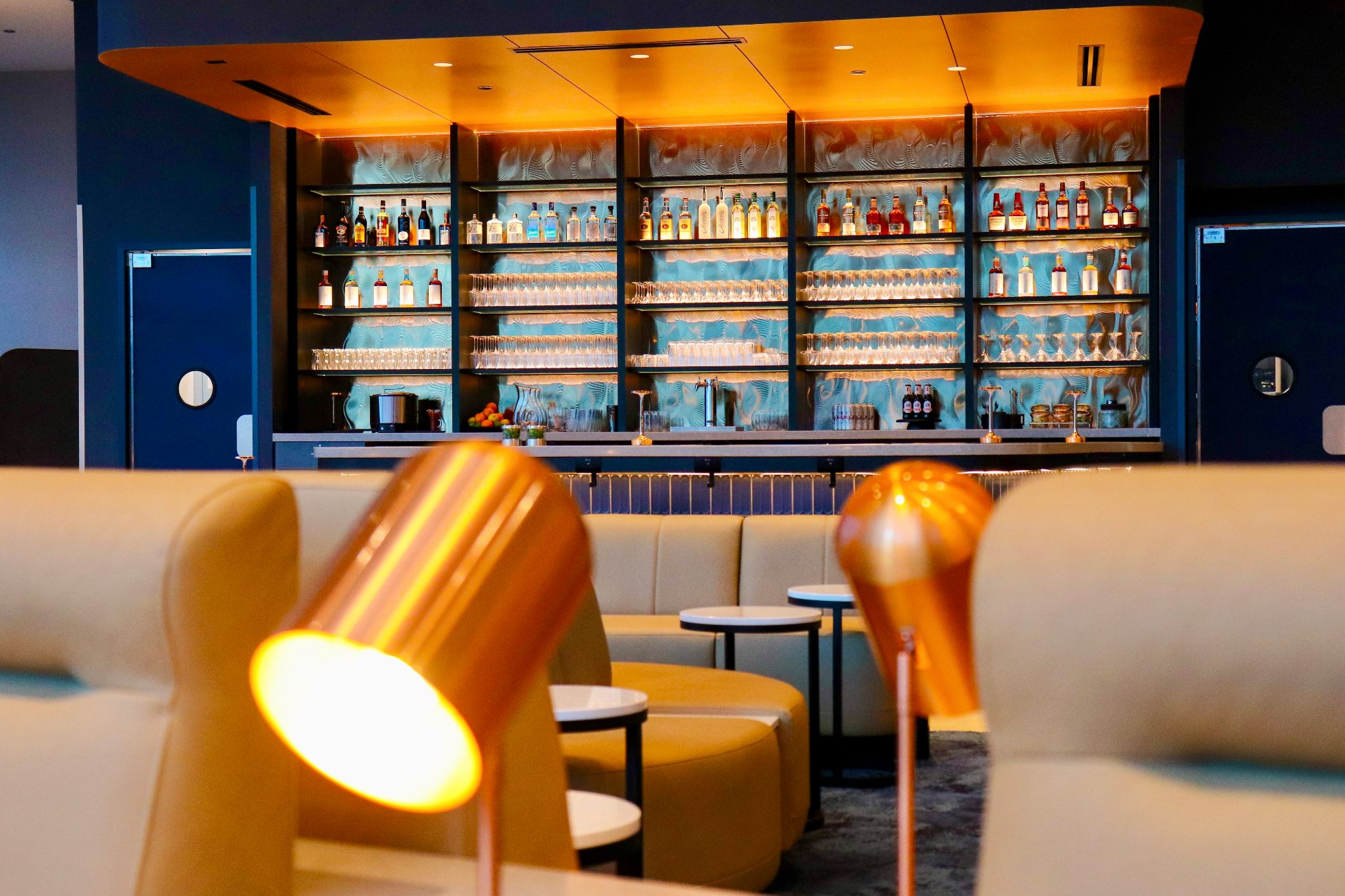 Zbliżenie na fotele i oświetlenie pomiędzy nimi, w tle oświetlony bar w saloniku biznesowym w Chicago