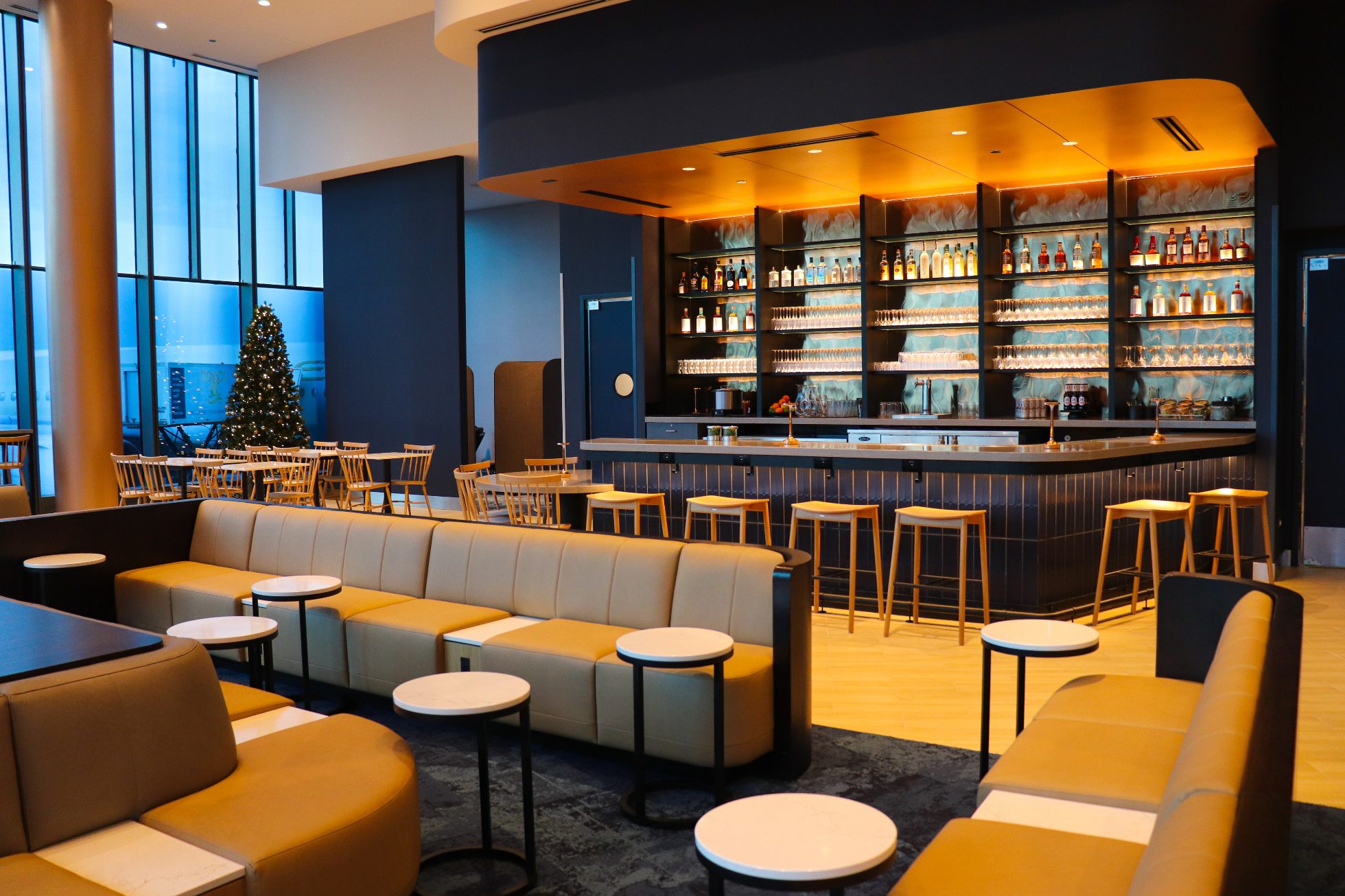 Elegancki Bar w Saloniku Biznesowym na lotnisku w Chicago na granatowej ścianie, wewnąrz ciepłe eleganckie oświetlenie i krzesła wokół baru