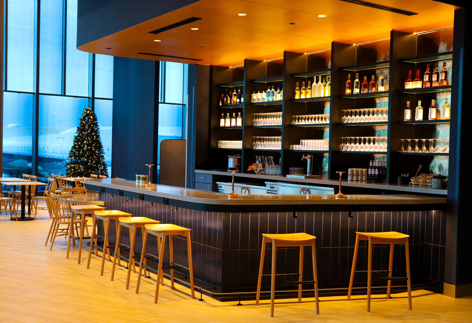 Elegancki Bar w Saloniku Biznesowym na lotnisku w Chicago na granatowej ścianie, wewnąrz ciepłe eleganckie oświetlenie i krzesła wokół baru