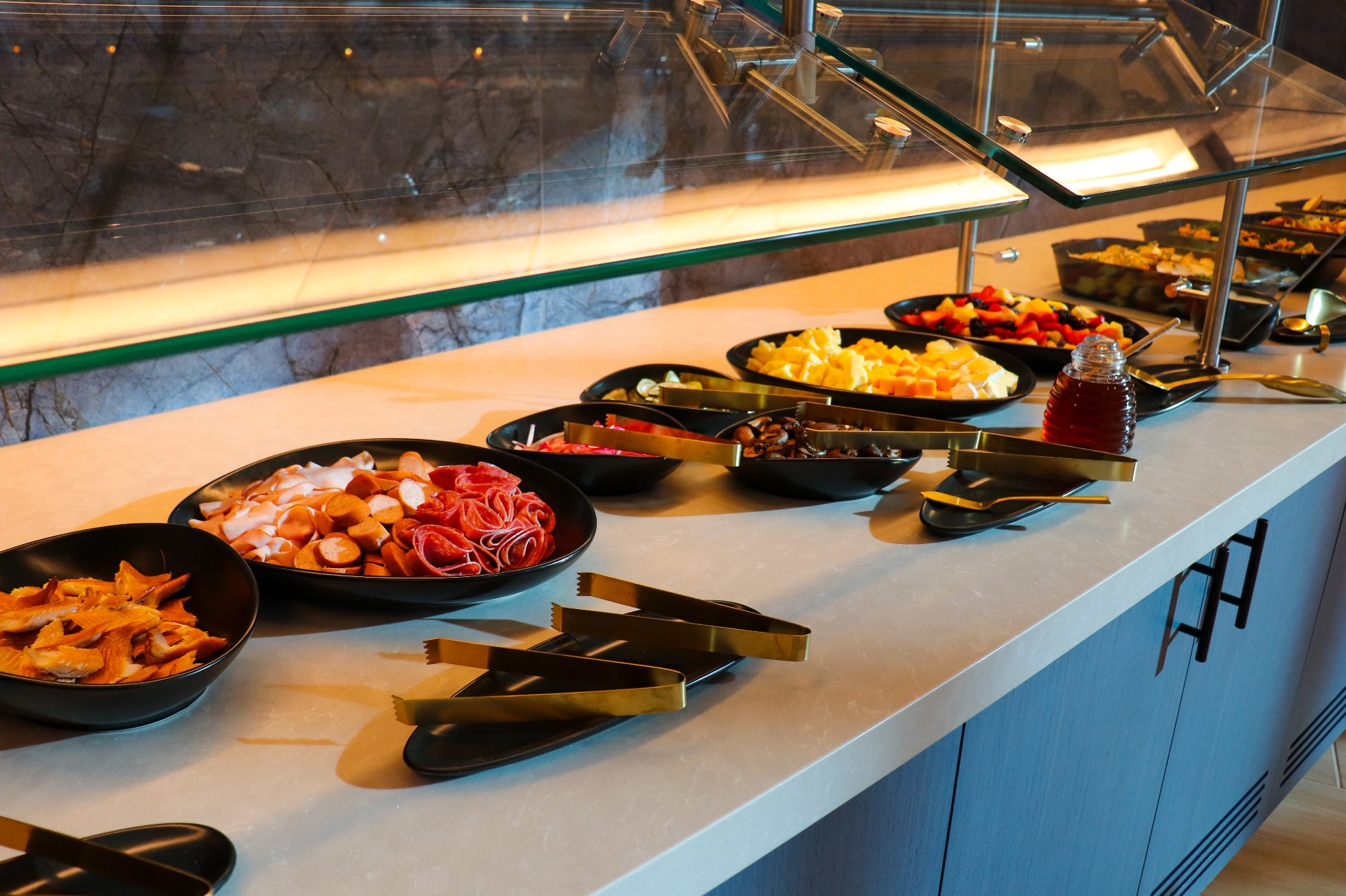 Stół szwedzki z daniami podanymi w czarnych półmiskach na białych blatach - Business Lounge Chicago