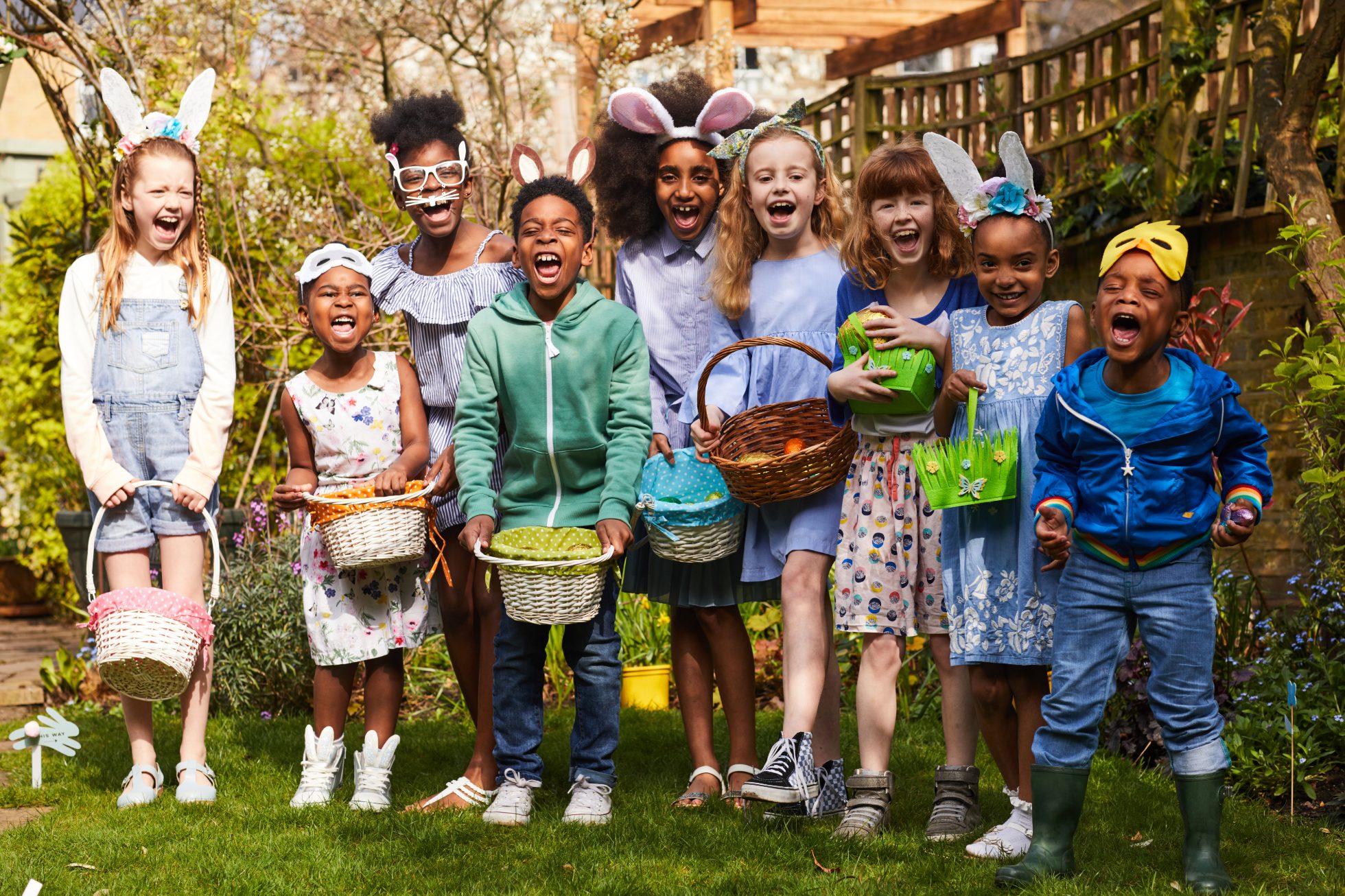 Grupa dzieci bawiących się na Easter Egg Hunt, śmiejąc się i krzycząc, na zewnątrz w słońcu.; pomysły na Wielkanoc