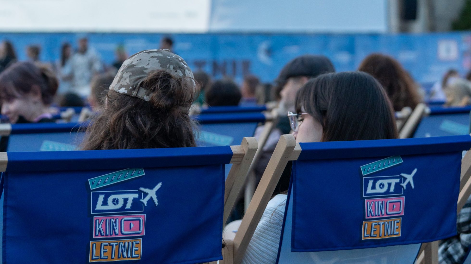 Guests at the LOT summer cinema under the Palace of Culture lying on deck chairs before the screening