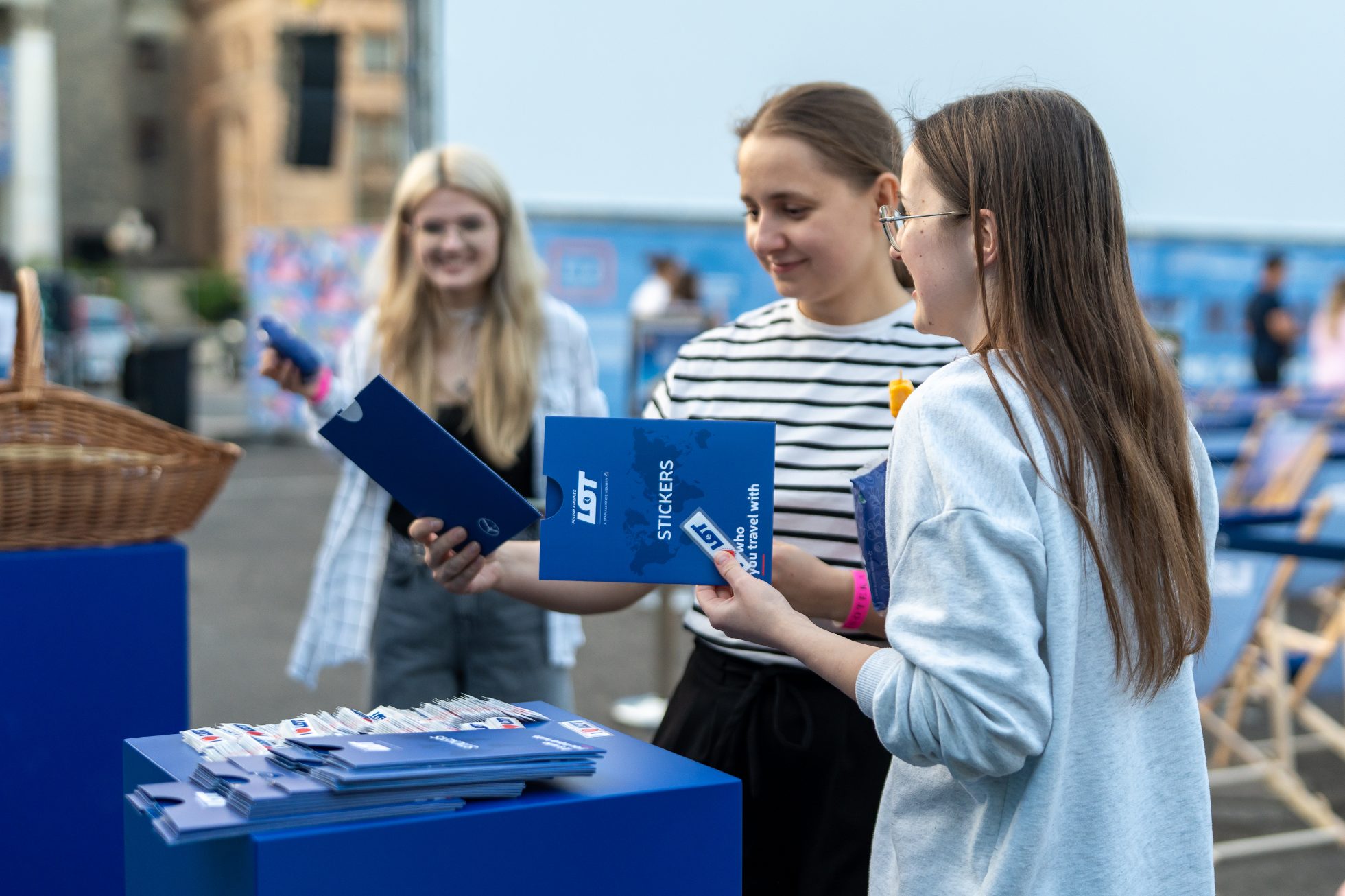 Two girls treating themselves to a set of LOT stickers in the LOT Polish Airlines promotional area