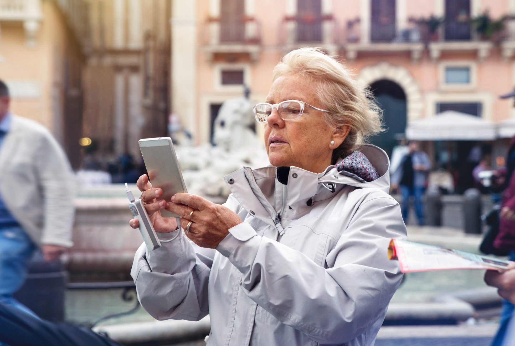 Starsza kobieta zwiedzająca i korzystająca ze swojego telefonu komórkowego z podłączoną dodatkową baterią we Włoszech