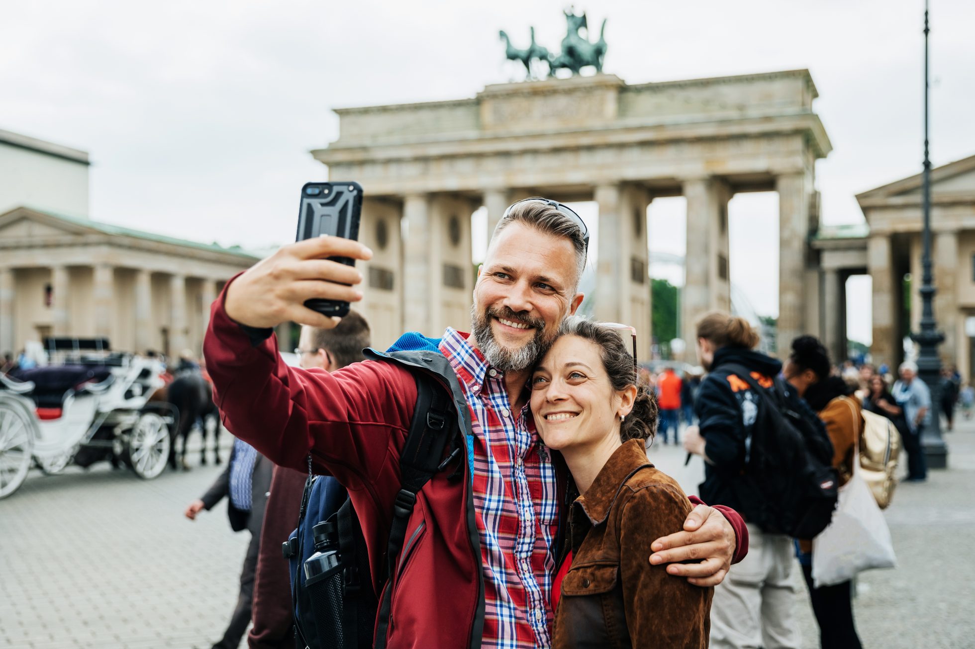 Dojrzała para używa swojego smartfona, aby zrobić wspólne selfie przed słynną lokalną architekturą.