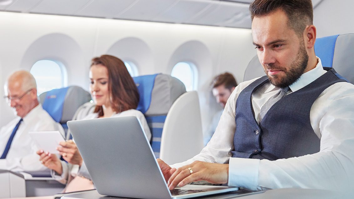 The passenger works on a computer on the plane.