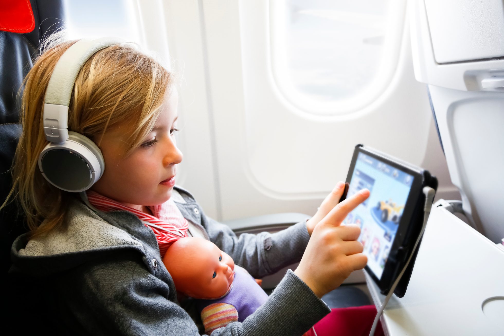 Dziewczynka w samolocie z lalką i tabletem - jak poradzić sobie z jet lagiem?