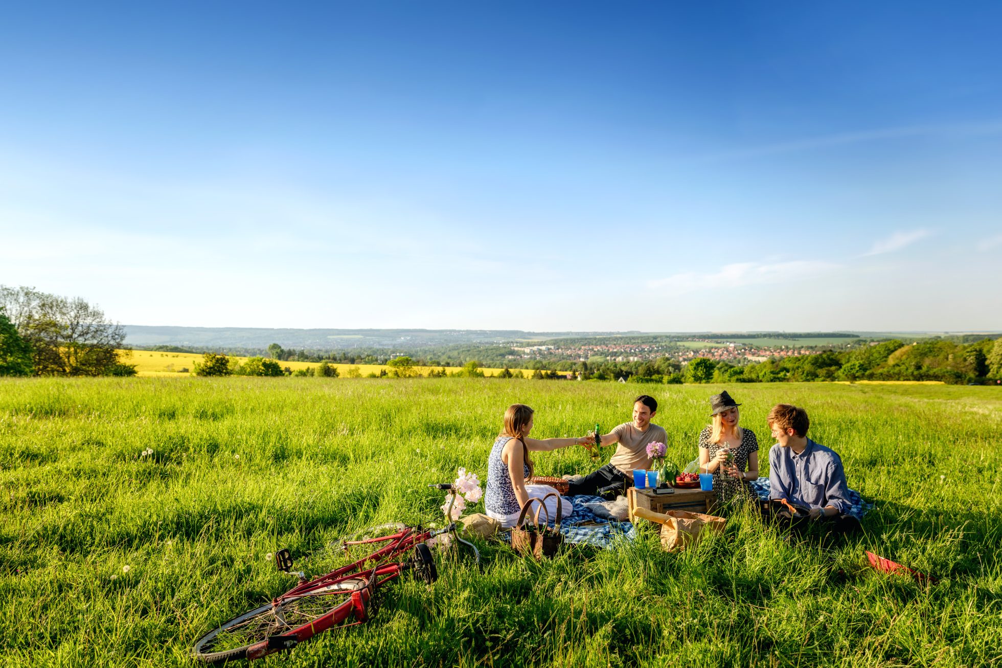 A group of friends are having a picnic on the grass in the mountains