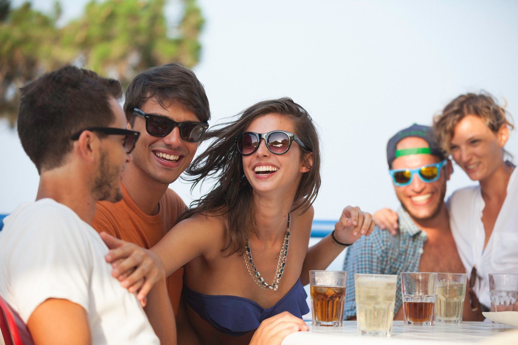 Large group of friends having lunch on the beach, group trips vs solo trips