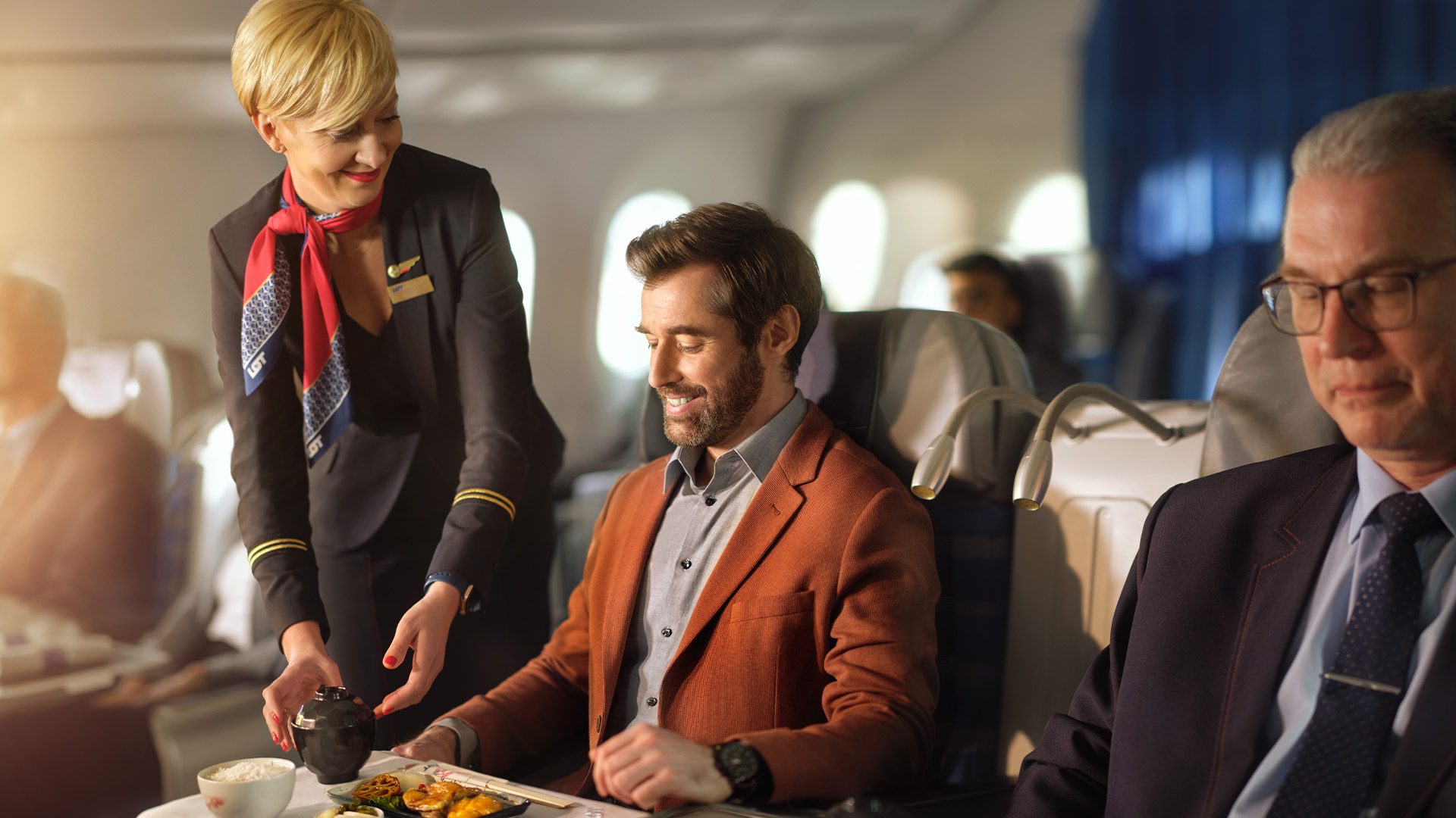 Stewardessa podaje posiłek pasażerowi LOT Business Class