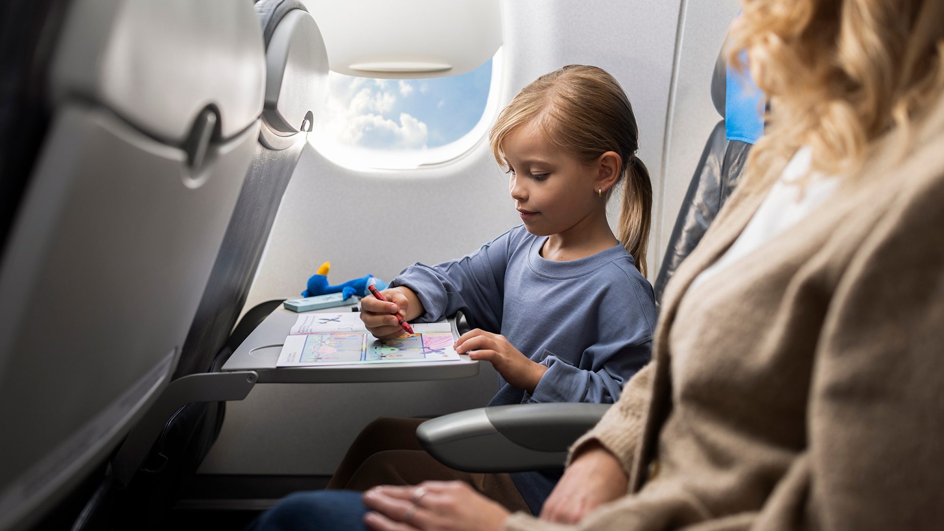 A girl playing with coloring books on board Embraer