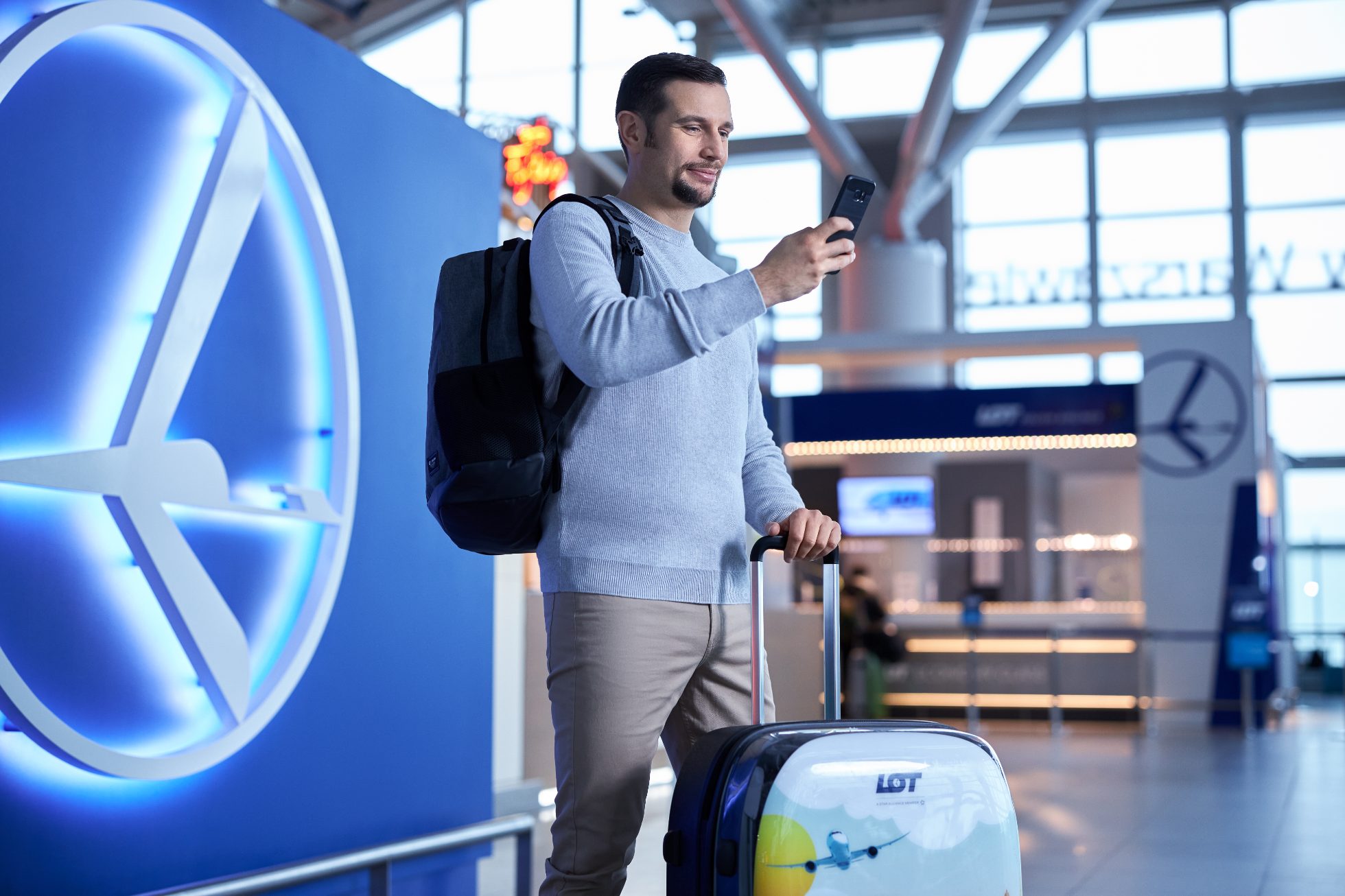 Mężczyzna na lotnisku z walizką i telefonem
