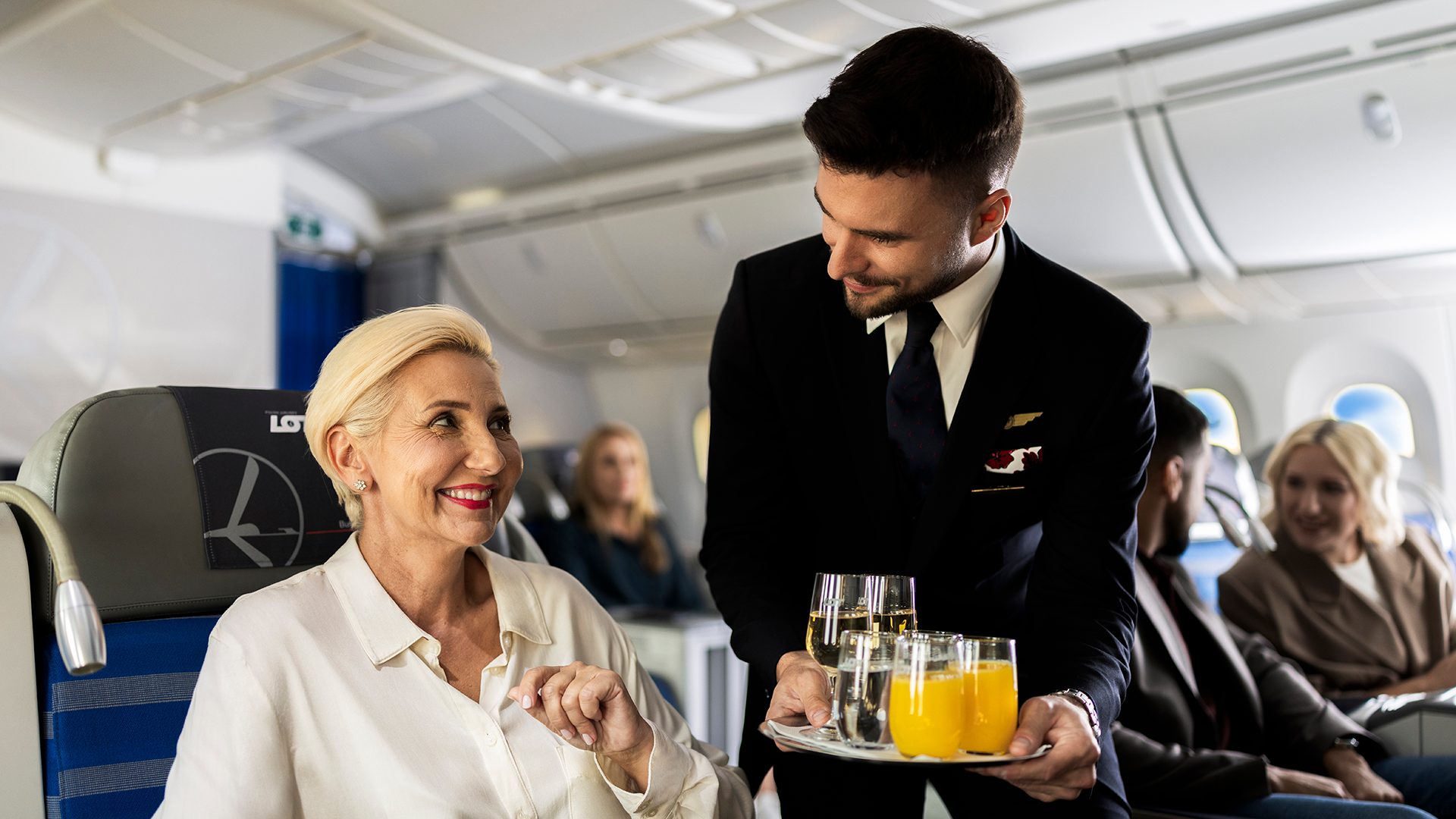 Steward serving drinks to passenger on Dreamliner