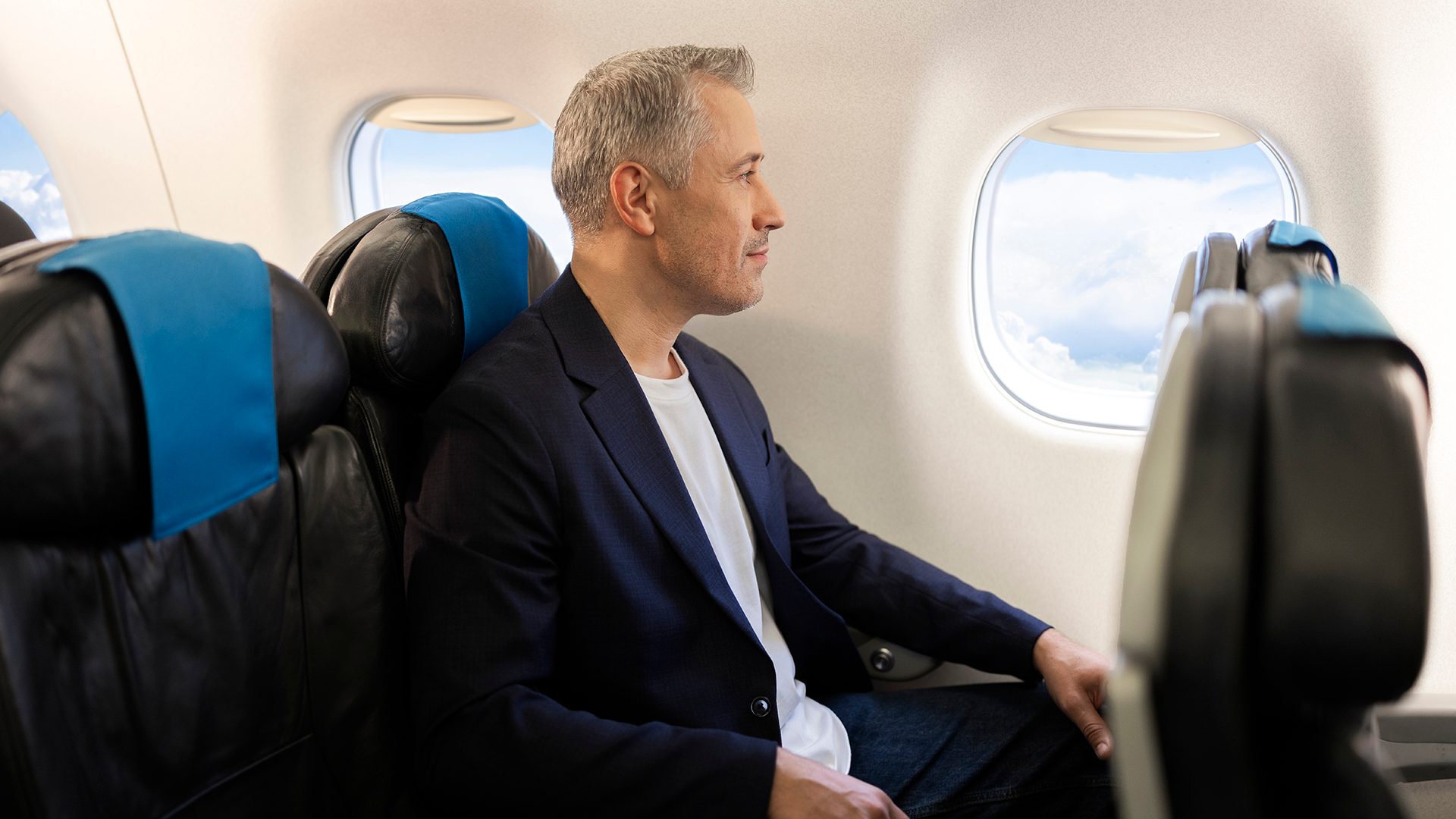 A passenger aboard an Embraer is looking through the window