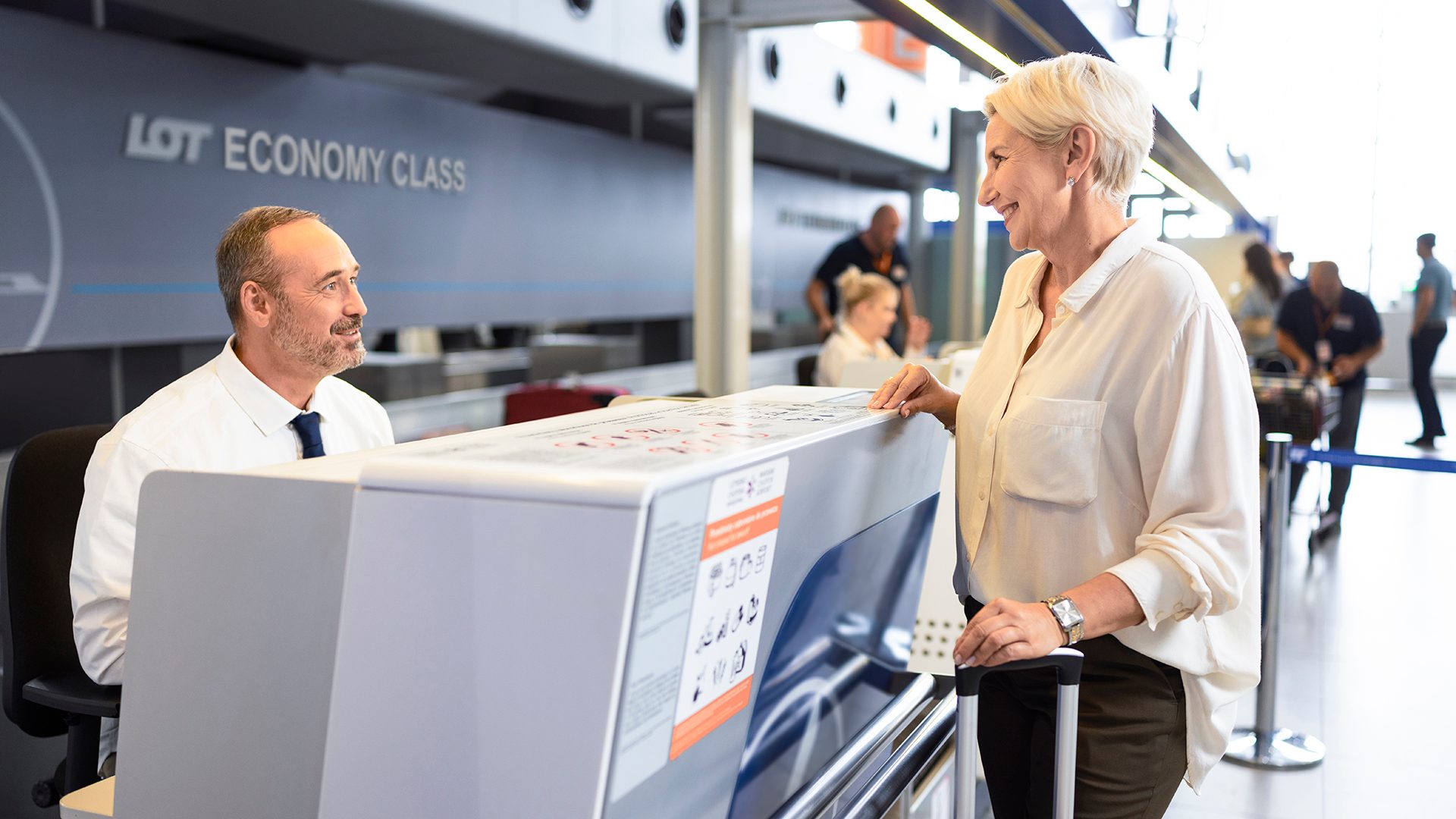 Passenger at check-in counter attended to by LOT employee